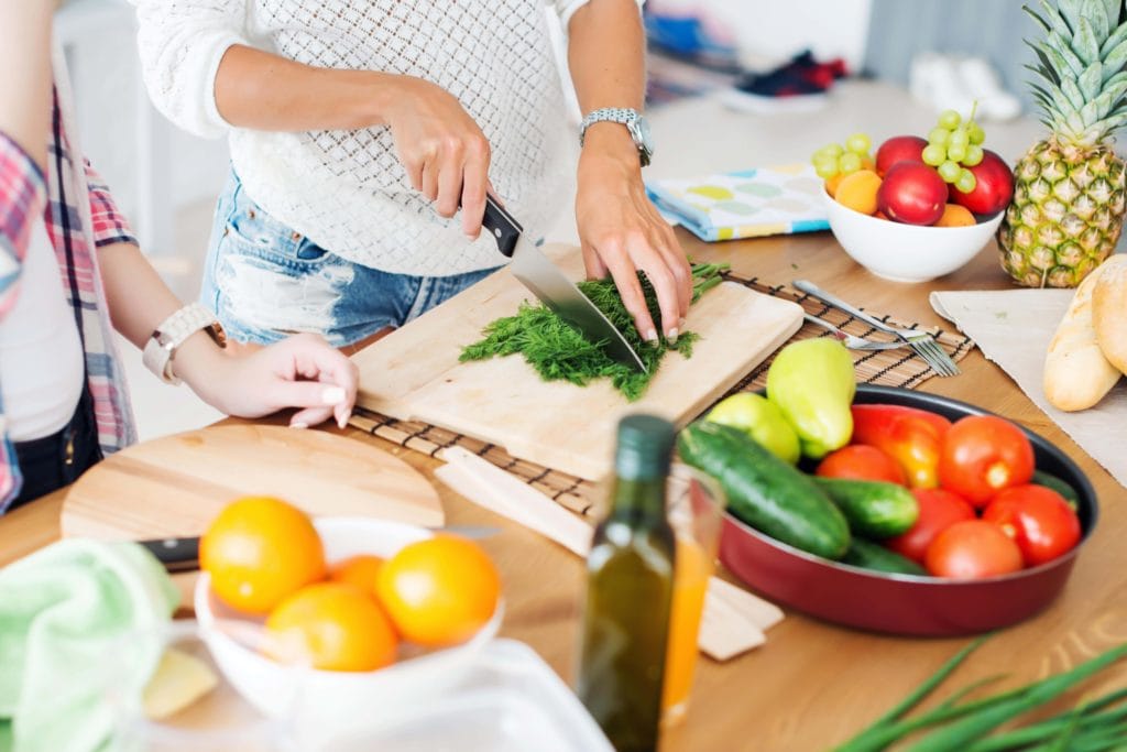 Women slicing healthy foods on cutting board for Arbonne's 30 Day Cleanse