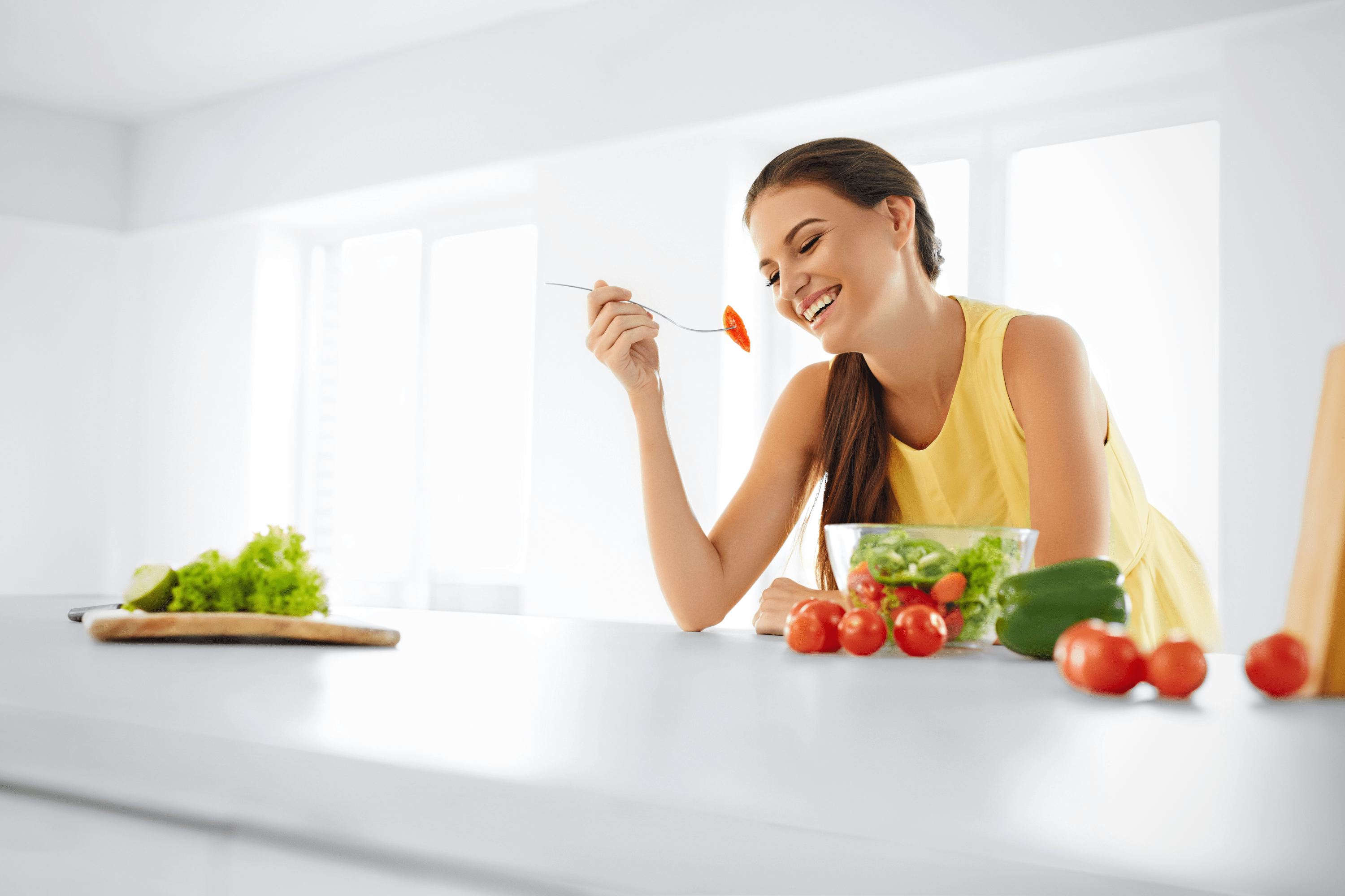 Woman eating veggies in the kitchen: she knows how to get diet back on track and STAY on track!