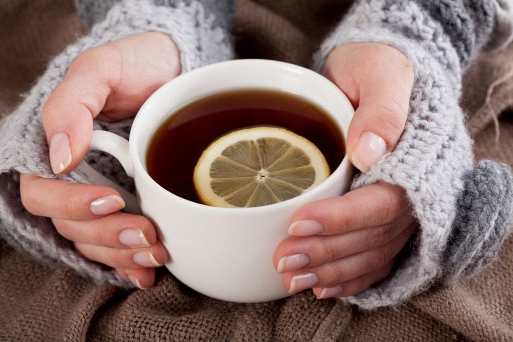 Woman holds Arbonne Detox Tea in a white mug.