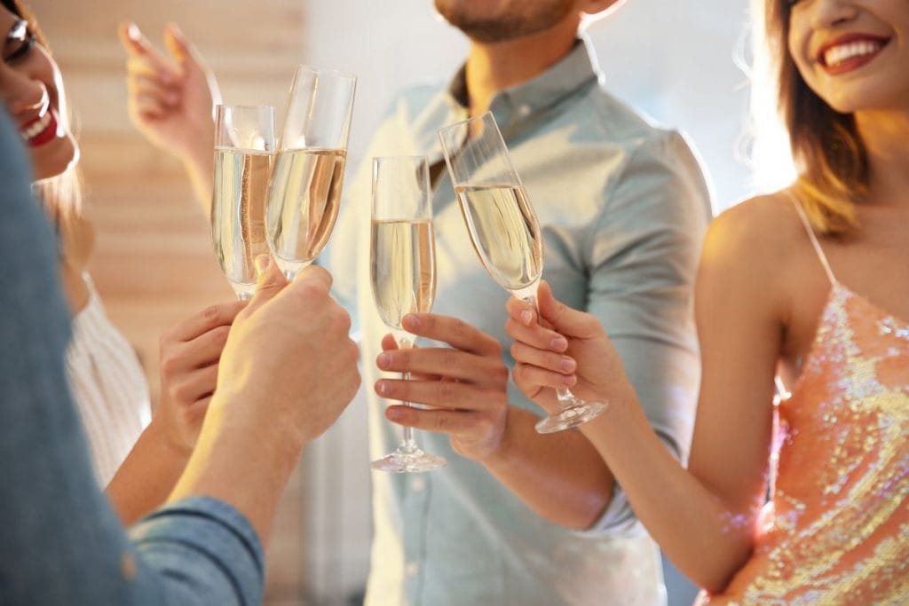 Four people celebrating New Year's Eve with champagne, using new year resolution affirmations.