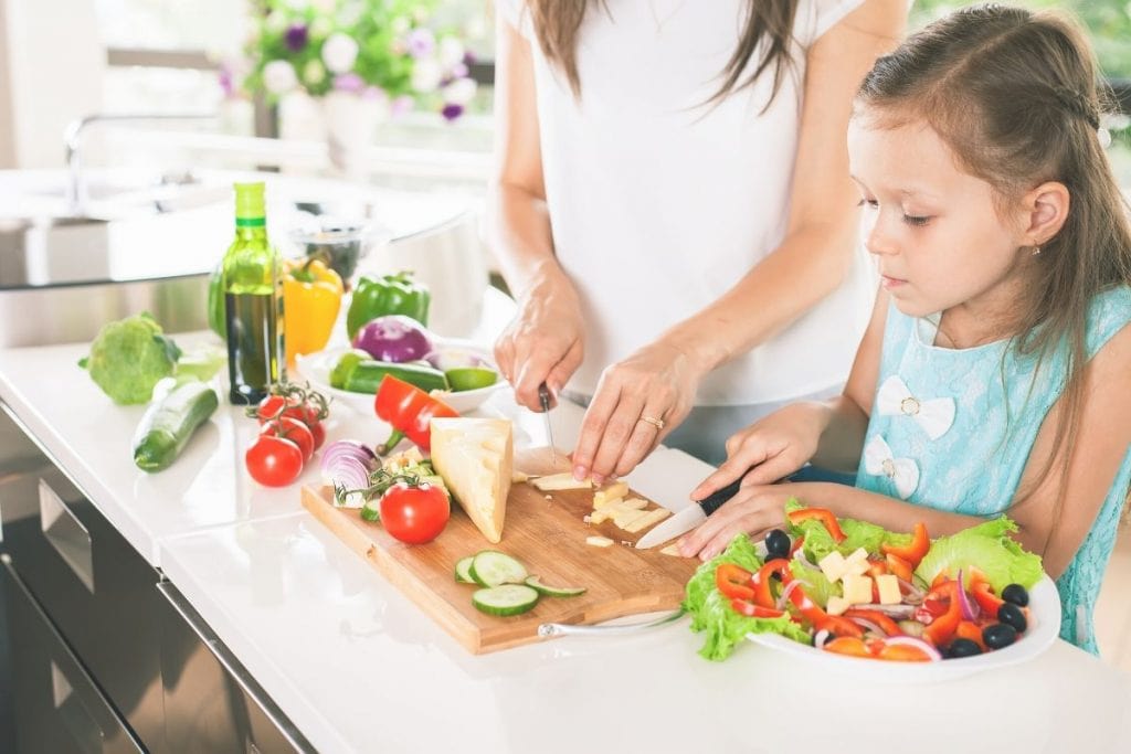 Young daughter helping meal planning strategies and meal prep with her mom.