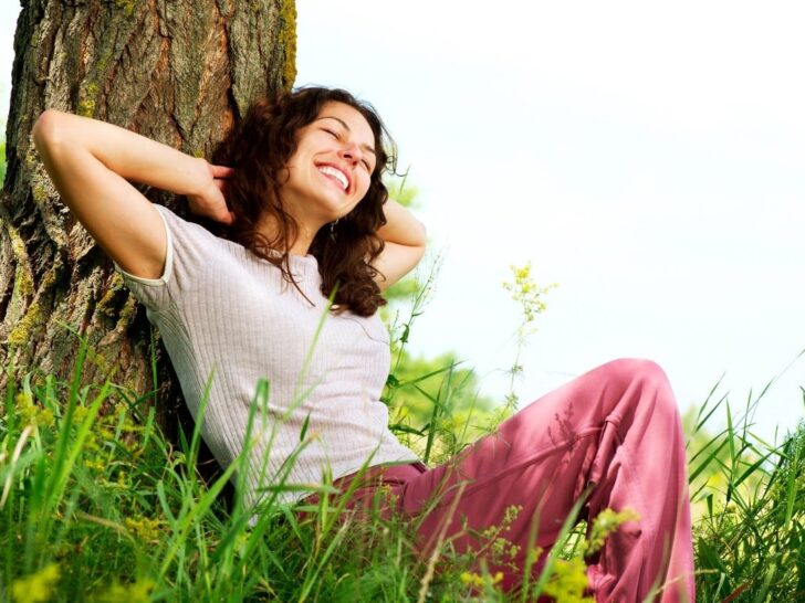Woman relaxing against tree, anxiety-free.