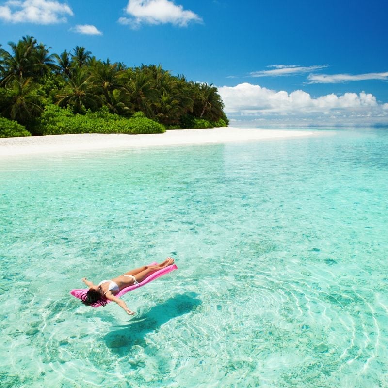 Woman floating in the Caribbean, using a positive mindset to reduce stress