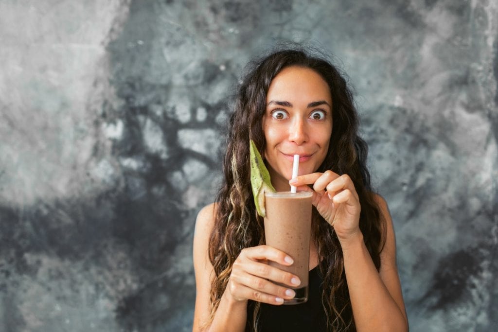Funny, excited woman drinking a protein shake.