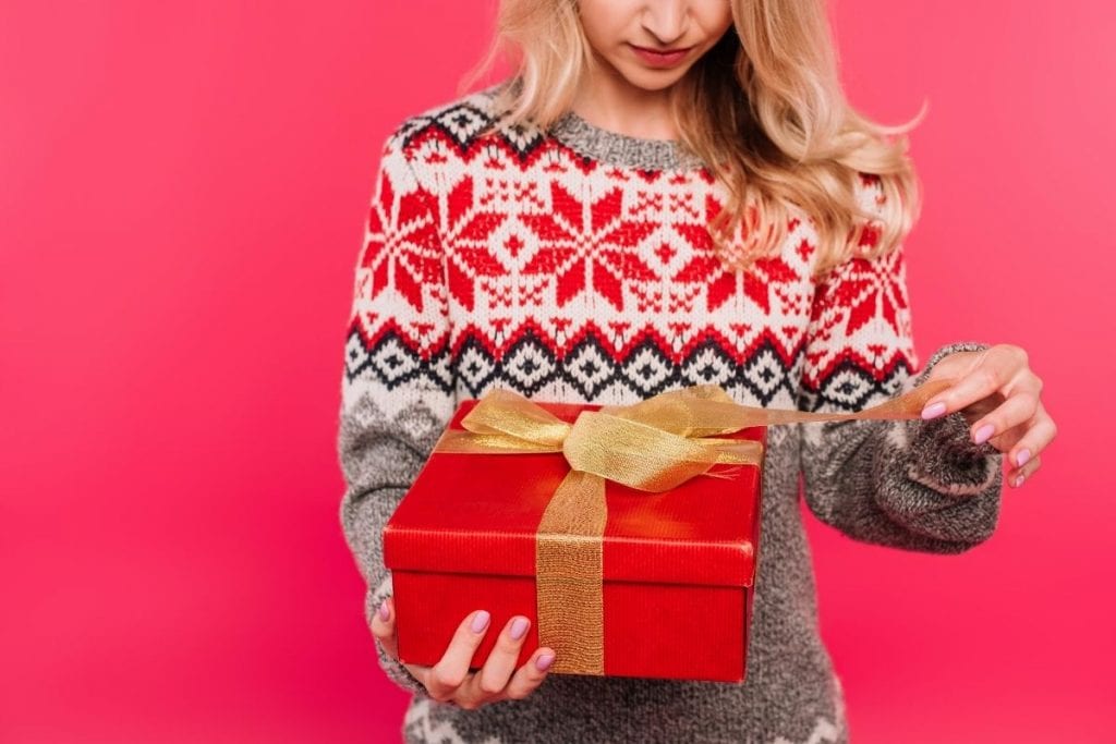 Woman in sweater is opening up a personalized gift for her from Etsy