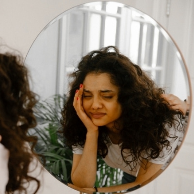 Woman looking in mirror. When you want to practice letting go of control, know your feelings