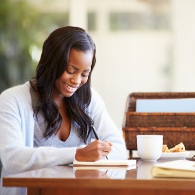 Woman writing a gratitude journal. If you want to learn how to find peace of mind and happiness, practicing unconditional gratitude can help