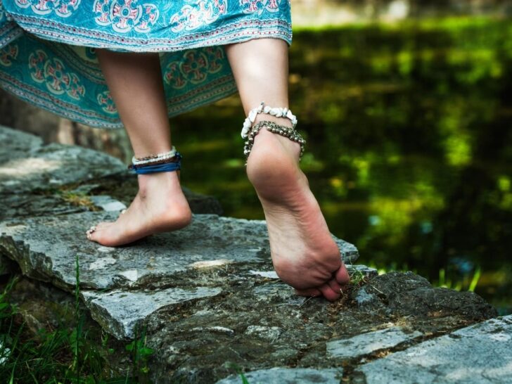 Woman walking along stones with bare feet.