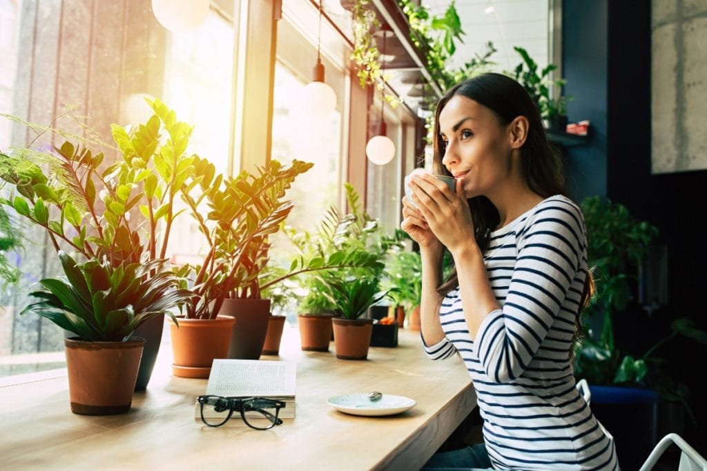 Woman sipping a cup of coffee as the sun comes up.