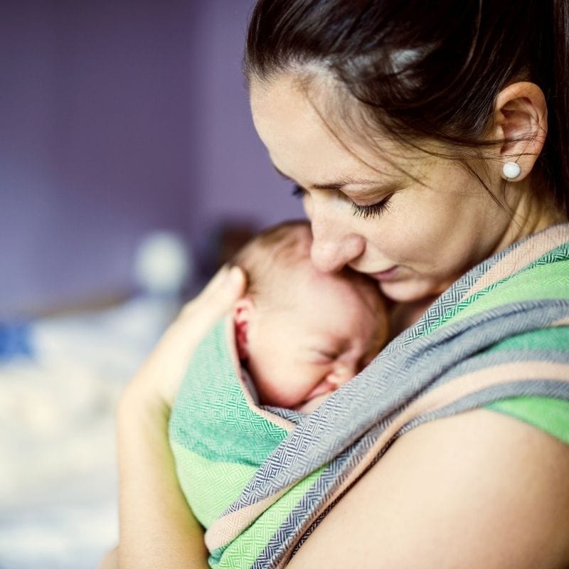 Stay at home mom with baby in a cloth baby carrier.