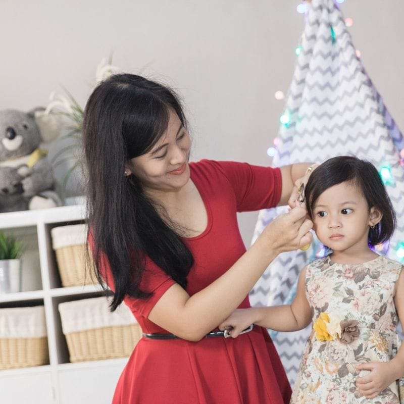 A mother doing her daughter's hair.