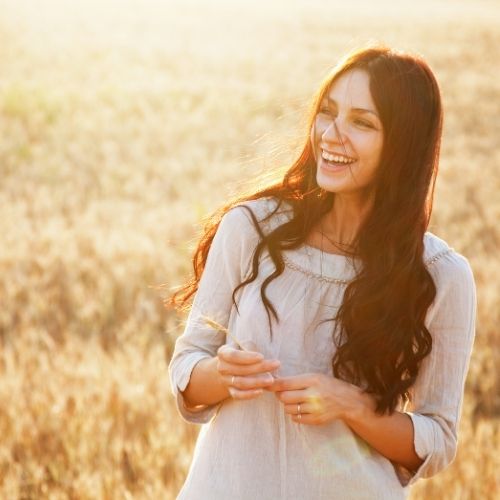 Woman basking in the light from the sunset is practicing self-love affirmations