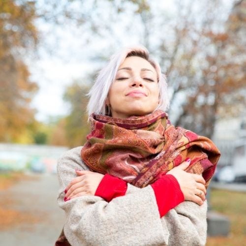 Woman hugging herself and accepting her emotions