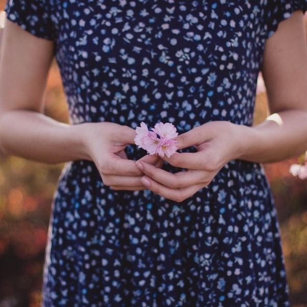 Woman holding a flower accepting the little things in life.