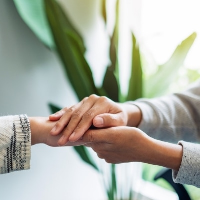 Woman holding someone's hand and consoling them