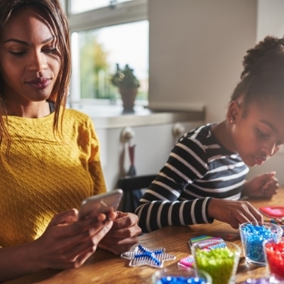 A mom on her phone while child plays