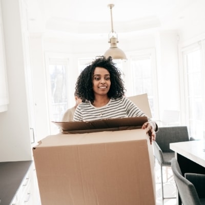 Woman moving a box of stuff. Decluttering is a great way to nourish your soul