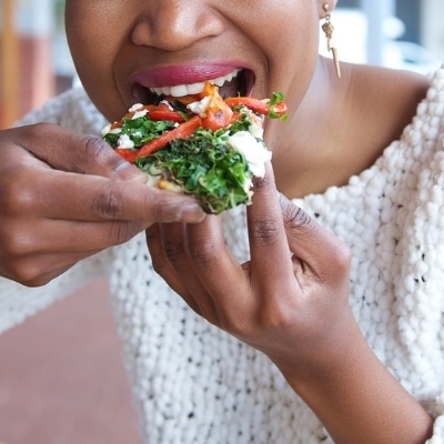 Woman mindfully eating healthy pizza and actively tasting each bite