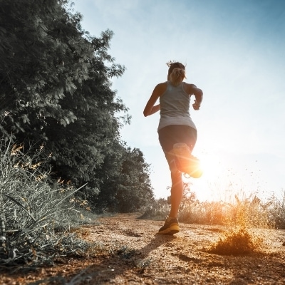 Woman running in the morning sunlight on a trail