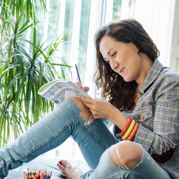 Woman coloring in a mandala coloring book for adults