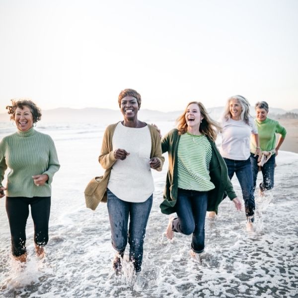 Women running on the beach, laughing, enjoying themselves