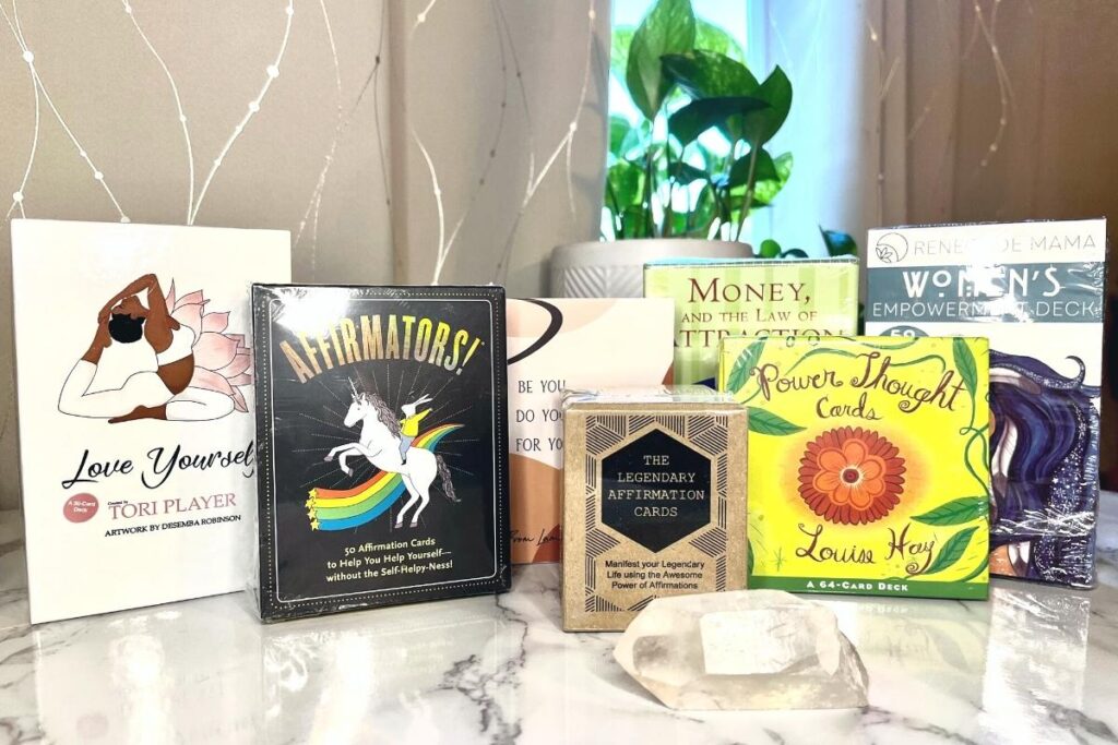 Collection of the best affirmation cards to buy in 2022, including: Affirmators!, Power Thought Cards by Louisa Hay, Lamare Affirmation Cards, Legendary Affirmation Cards, and Love Yourself Affirmation Cards by Tori Player, Money and the Law of Attraction Cards by Ester Hicks, and Women's Empowerment Deck by Renegade Mama
