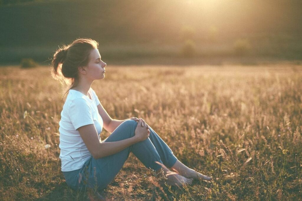 Woman sitting outside in the sunset is working on improving spiritual wellness