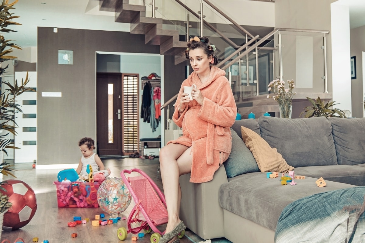 Young mother with baby and mess needs to put together a stay at home mom survival kit