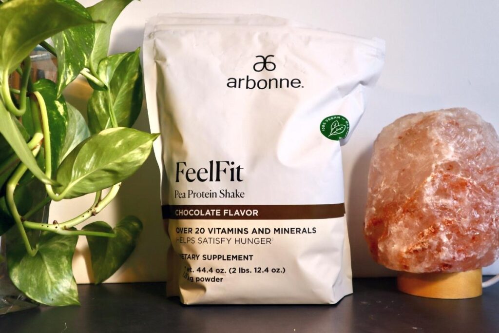 Styled photoshoot of bag of Arbonne Feel Fit Pea Protein Shake Chocolate Flavor