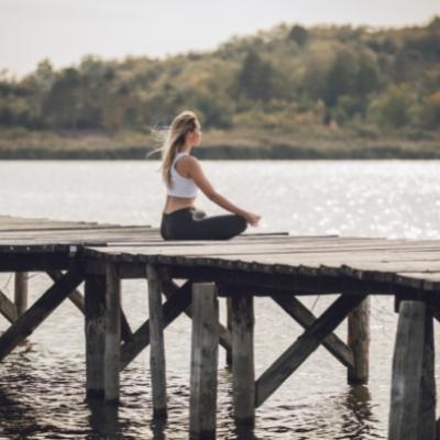 Woman feeling spiritually lost is meditating on a pier in cloudy weather