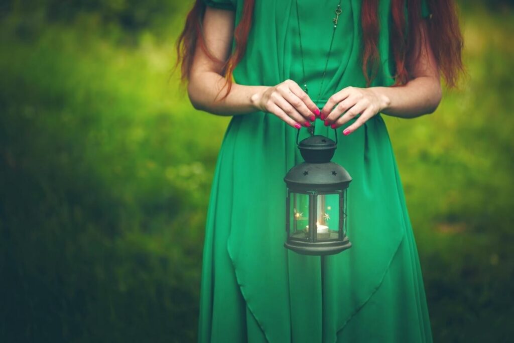 Woman in green dress with a lantern, metaphor for signs of spiritual awakening