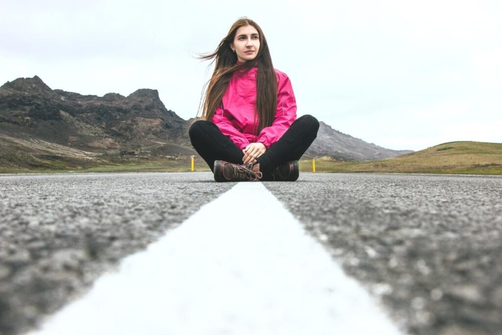 Woman sitting in the middle of the road, metaphor for feeling lost after spiritual awakening