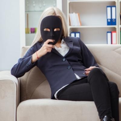 Woman sitting on a couch holding up a mask