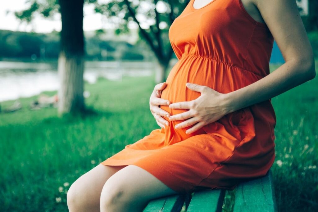 Woman in orange holding her pregnant belly