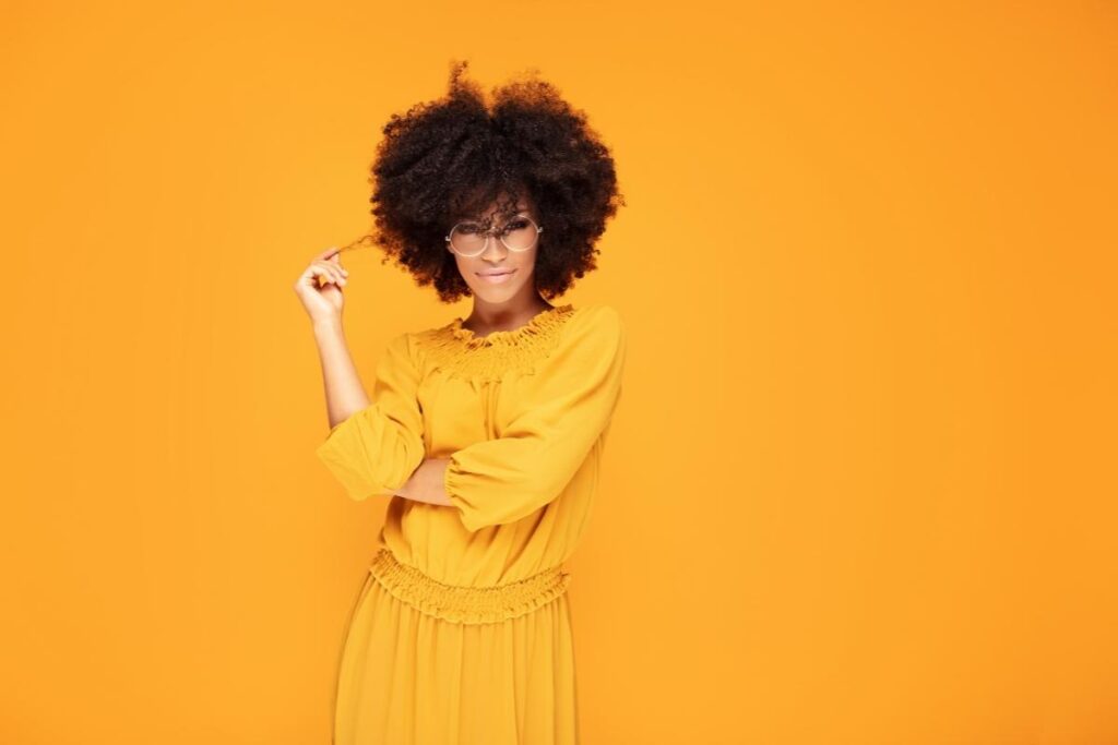 Woman in yellow with a yellow background looking confident