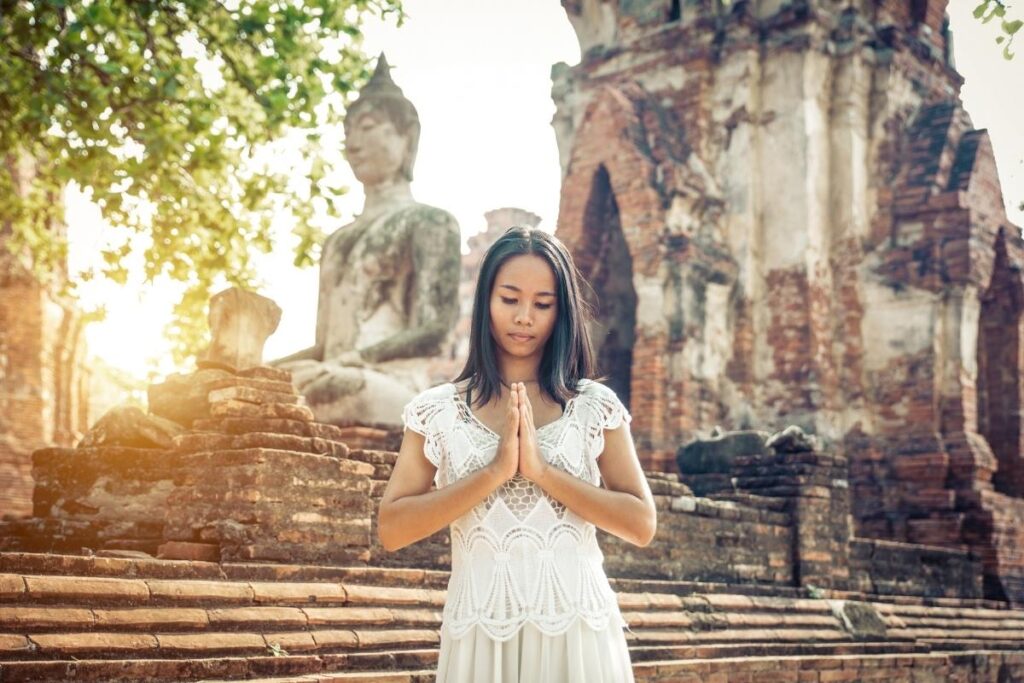 Woman praying in a Buddhist temple in Thailand