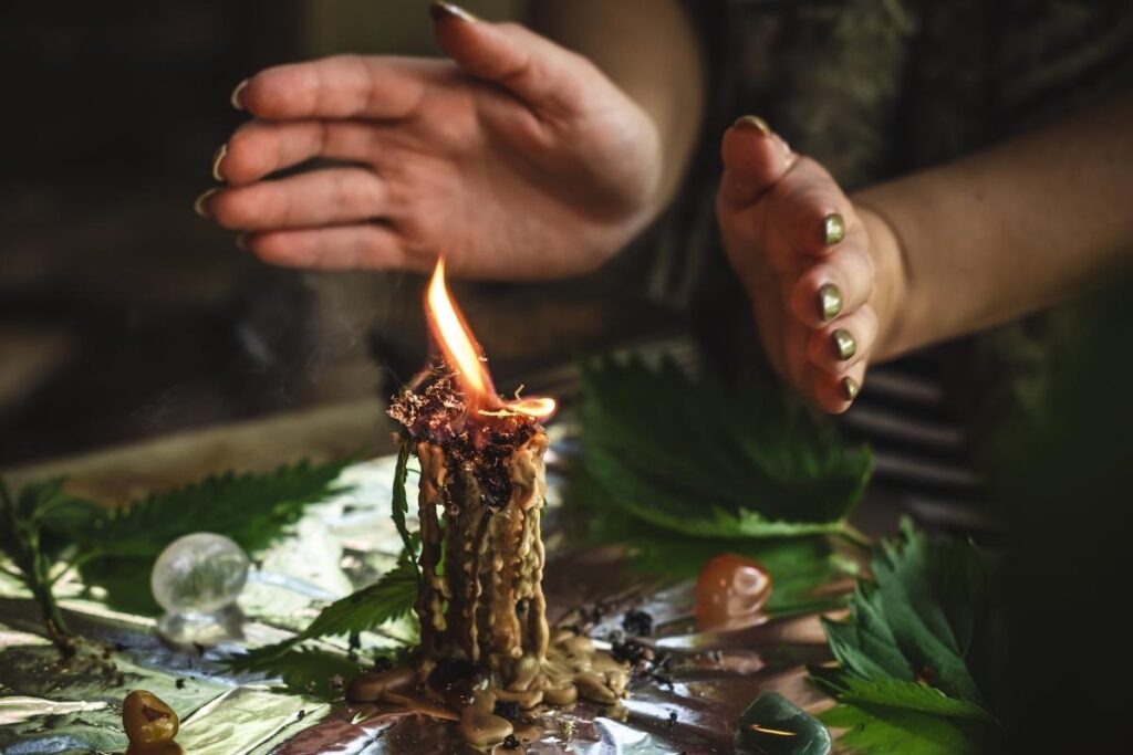 Woman's hands with a candle as she recites witchy affirmations