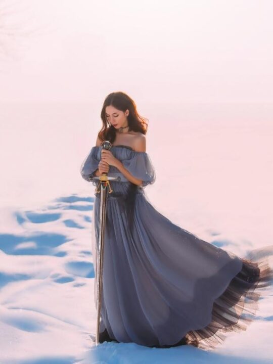 Woman in the snow with sword is embodying the Queen of Swords energy in tarot