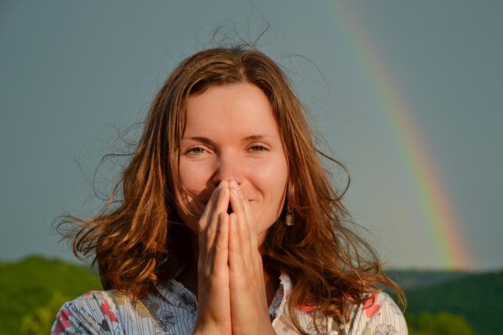 Woman outside under rainbow practicing affirmations for gratitude