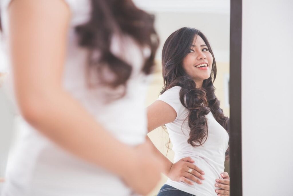 Woman with positive body image looking in mirror