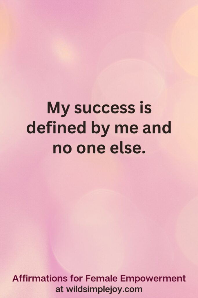 Vertical pin image with pink bokeh light background and text overlay, My success is defined by me and no one else. Affirmations for Female Empowerment at wildsimplejoy.com