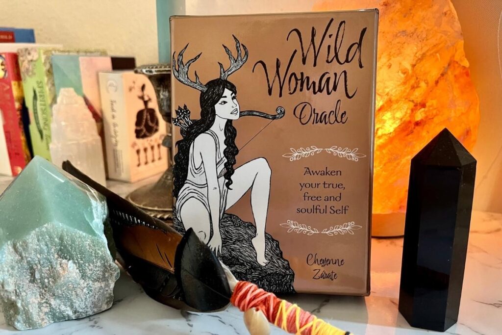 Wild Woman Oracle box with crystals and feathers on a table