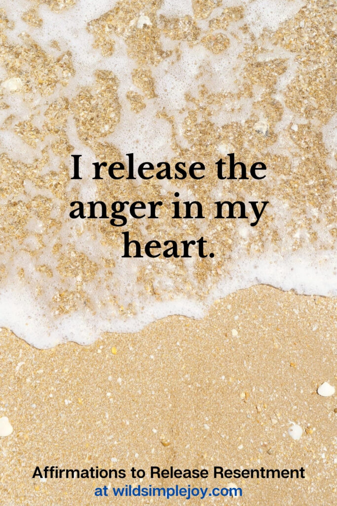 Vertical Pinterest Image with sand background and text overlay that reads I release the anger in my heart Affirmations to release resentment at wildsimplejoy.com