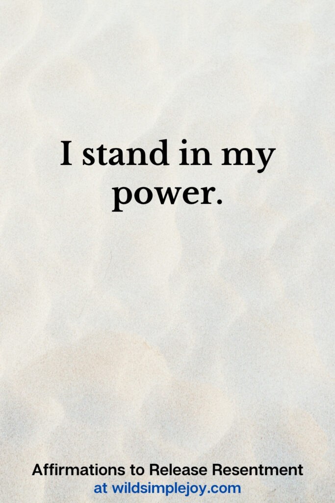 Vertical Pinterest Image with sand background and text overlay that reads I stand in my power Affirmations to release resentment at wildsimplejoy.com