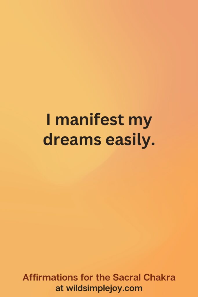 Vertical social media image on orange background with text overlay that reads I manifest my dreams easily. Affirmations for the Sacral Chakra at wildsimplejoy.com