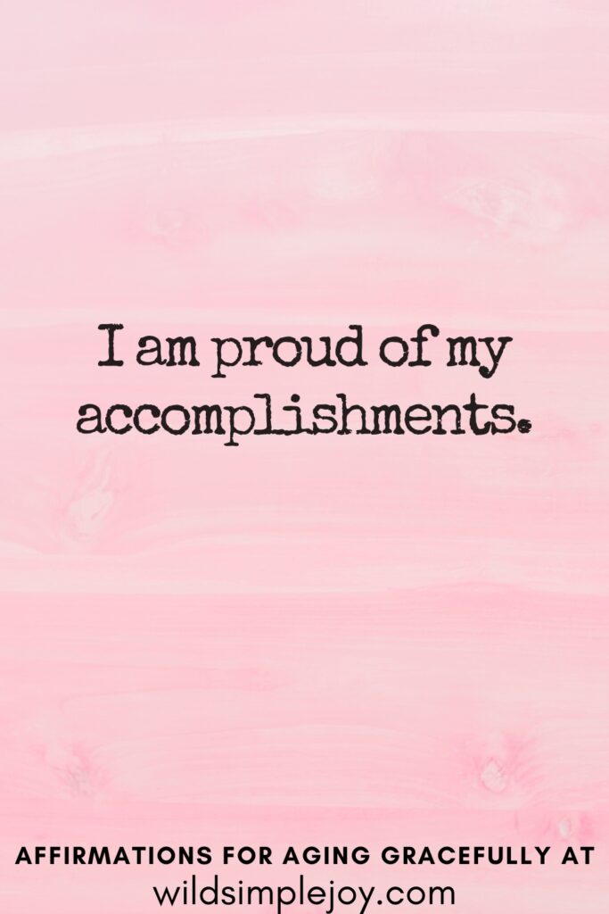 Vertical Pinterest Image on a pink background with text overlay I am proud of my accomplishments Affirmations for Aging Gracefully at wildsimplejoy.com