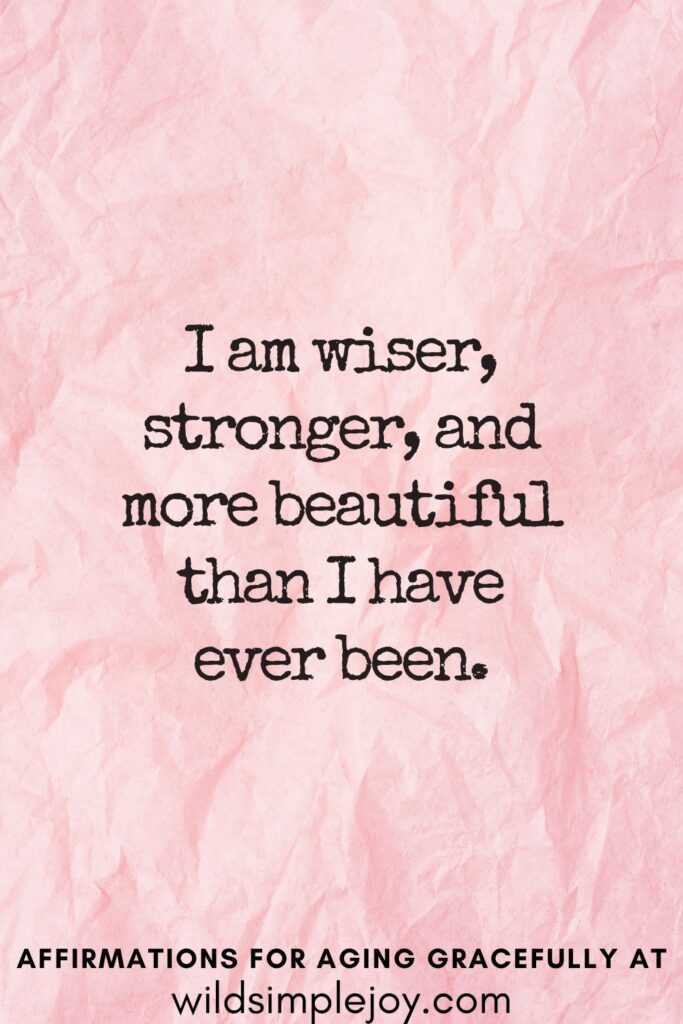 Vertical Pinterest Image on a pink background with text overlay I am wiser, stronger, and more beautiful than I have ever been Affirmations for Aging Gracefully at wildsimplejoy.com