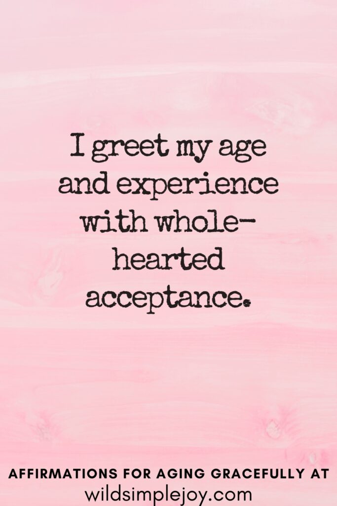Vertical Pinterest Image on a pink background with text overlay I greet my age and experience with whole hearted acceptance Affirmations for Aging Gracefully at wildsimplejoy.com