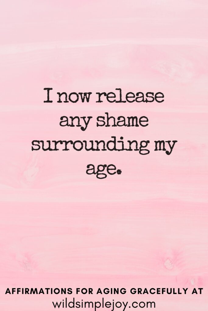 Vertical Pinterest Image on a pink background with text overlay I now release any shame surrounding my age Affirmations for Aging Gracefully at wildsimplejoy.com
