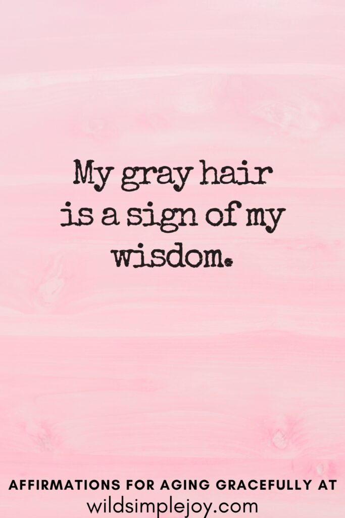 Vertical Pinterest Image on a pink background with text overlay My gray hair is a sign of my wisdom Affirmations for Aging Gracefully at wildsimplejoy.com